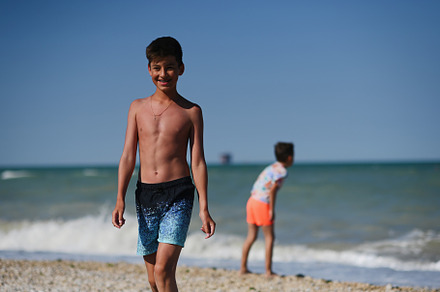 Two brothers throw pebbles into the sea in beach Porto Sant Elpi, a Photo by AS photostudio