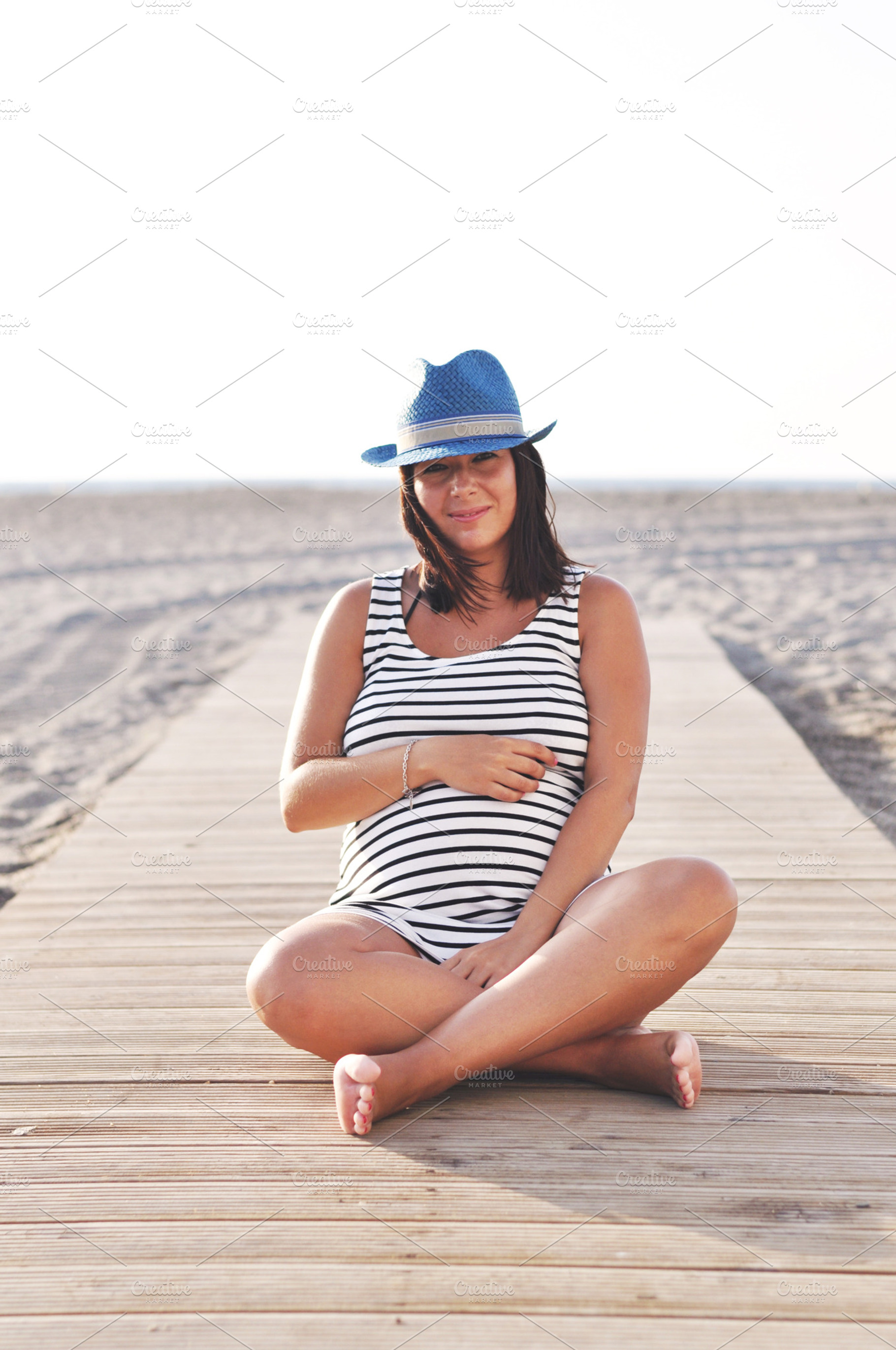 Pregnant woman sitting on the beach, a Person Photo by Iván Noguera Photography
