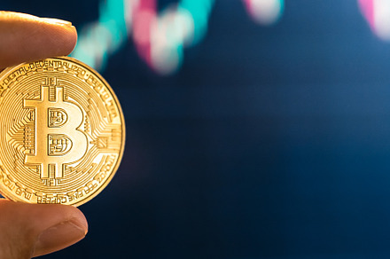 Bitcoin coins in hand in front of the computer, a Business Photo by Art Rachen