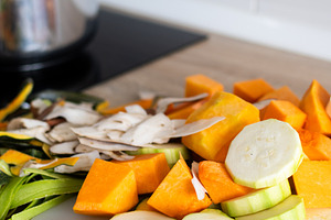 Fresh chopped vegetables on cutting board with pot on stove in kitchen, a Food & Drink Photo by etorres69
