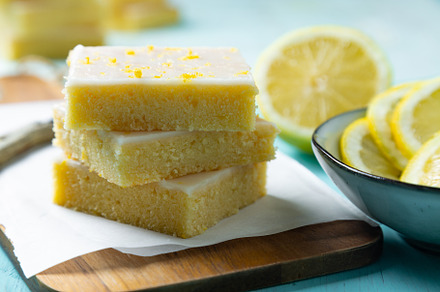 Homemade lemon brownies with lemon glaze and zest on a cutting b
