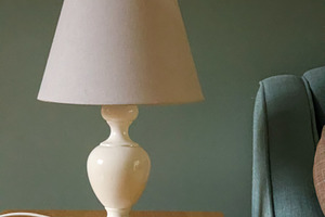 White lamp on wooden side table providing cozy, ambient light in, a Photo by Studio ANNA