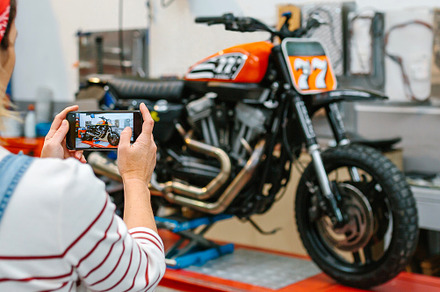 Female mechanic taking photo to motorcycle repaired over platform on garage, a Transportation Photo by davidpereiras