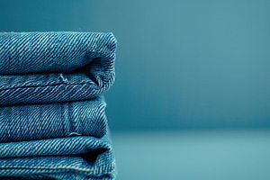 Stacked blue jeans on blue background, a Beauty & Fashion Photo by AlyaAnd