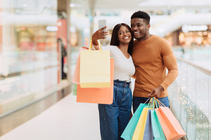 Happy black couple taking selfie after shopping at mall, a Photo by Prostock-Studio