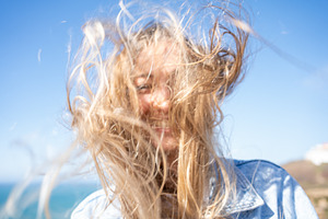 Happy woman with tousled messy long blond hair against clear blue sky, a Person Photo by andreonegin market