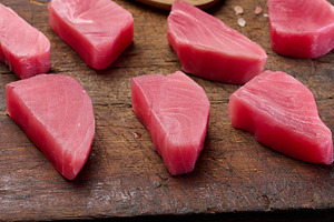 Raw tuna pieces on a brown wooden cutting board, a Food & Drink Photo by ndanko