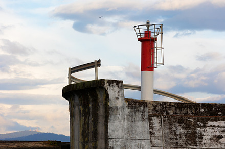 Red lighthouse on a concrete pier at, an Architecture Photo by Perpis
