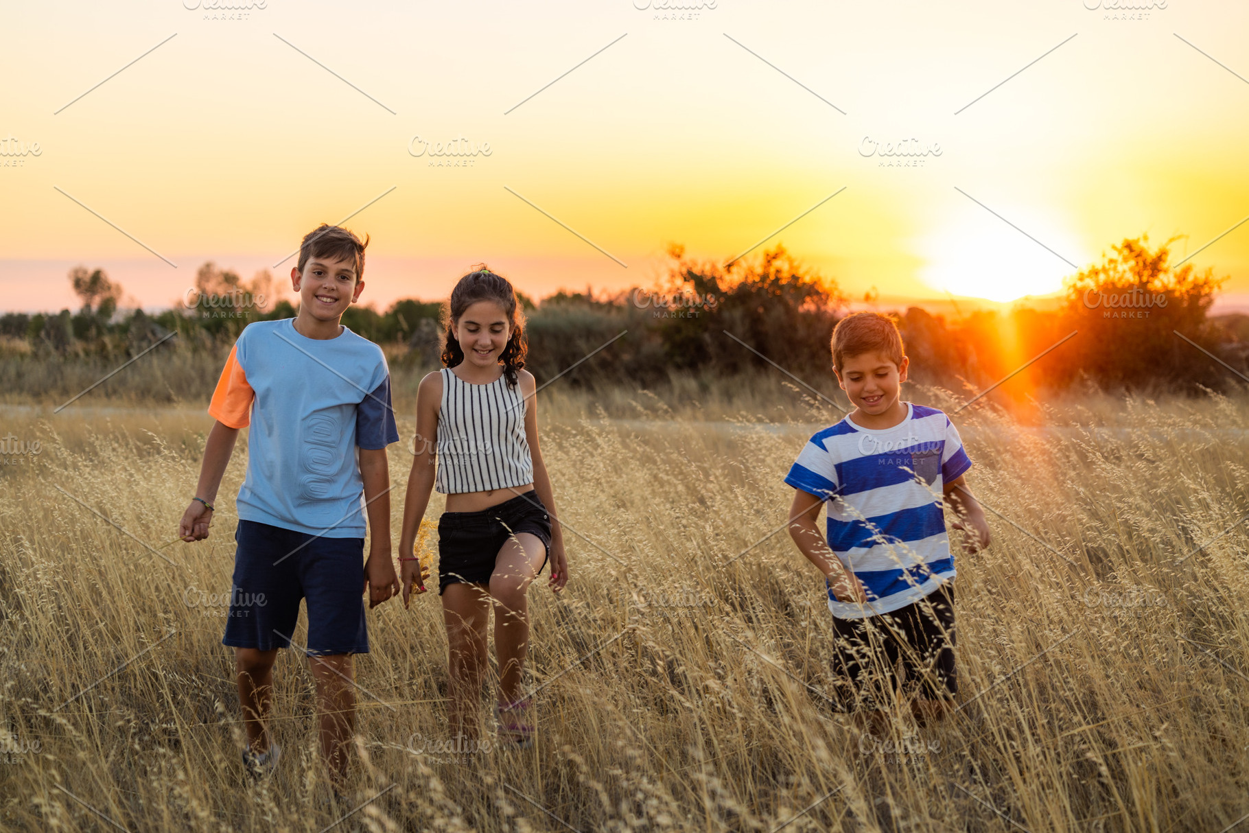 Three little friends in a field in their summer vacation at suns, a Person Photo by Cosca