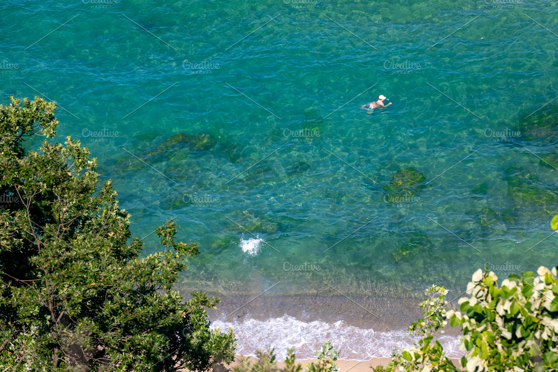 A person swims in transparent turquoise water near a sandy shoreline, surrounde, a Holiday Photo by Ales Munt