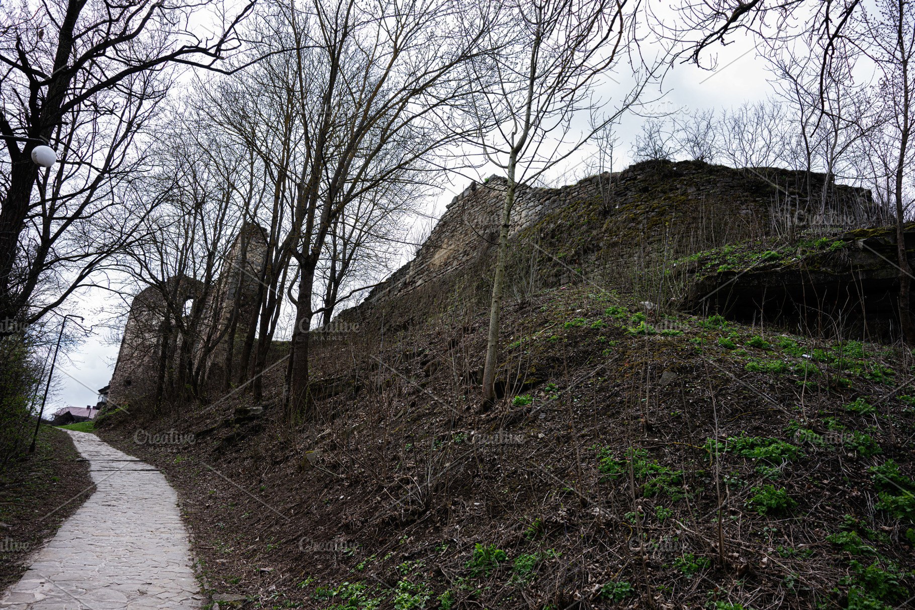 Historic ruins surrounded by trees along a pathway in Buchach, Ukraine, a Photo by AS photostudio