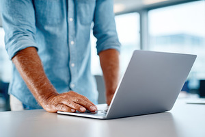 Smiling man working on laptop in modern office, a Business Photo by AlyaAnd