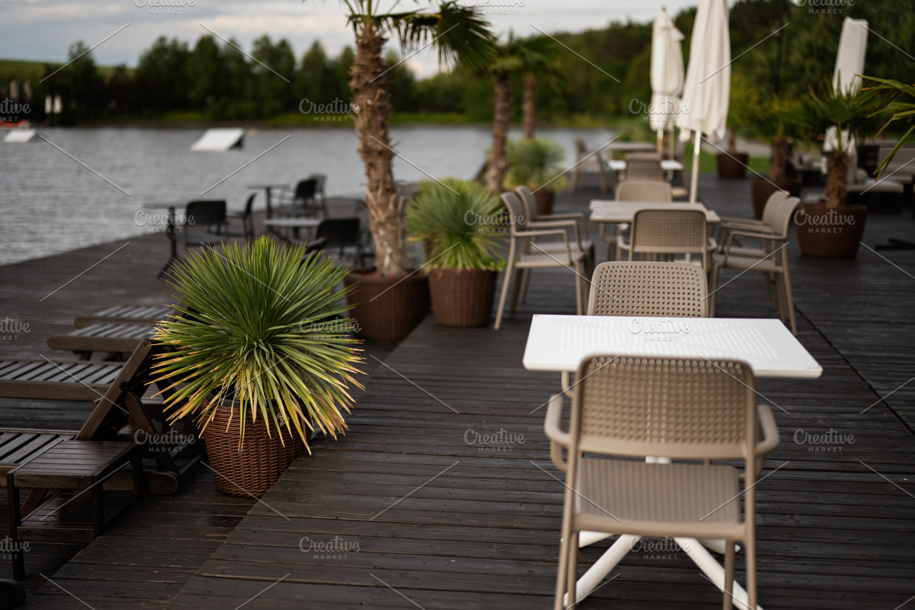 Outdoor café seating area by a lake with scenic tropical plants and views, a Photo by AS photostudio
