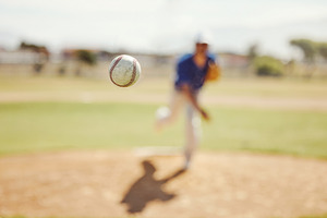 Sports, pitch and baseball ball in air, pitcher throwing it in match, game or practice in outdoor field. Fitness, exercise and training on baseball field with player in action, movement and motion, a Photo by Peopleimages.com