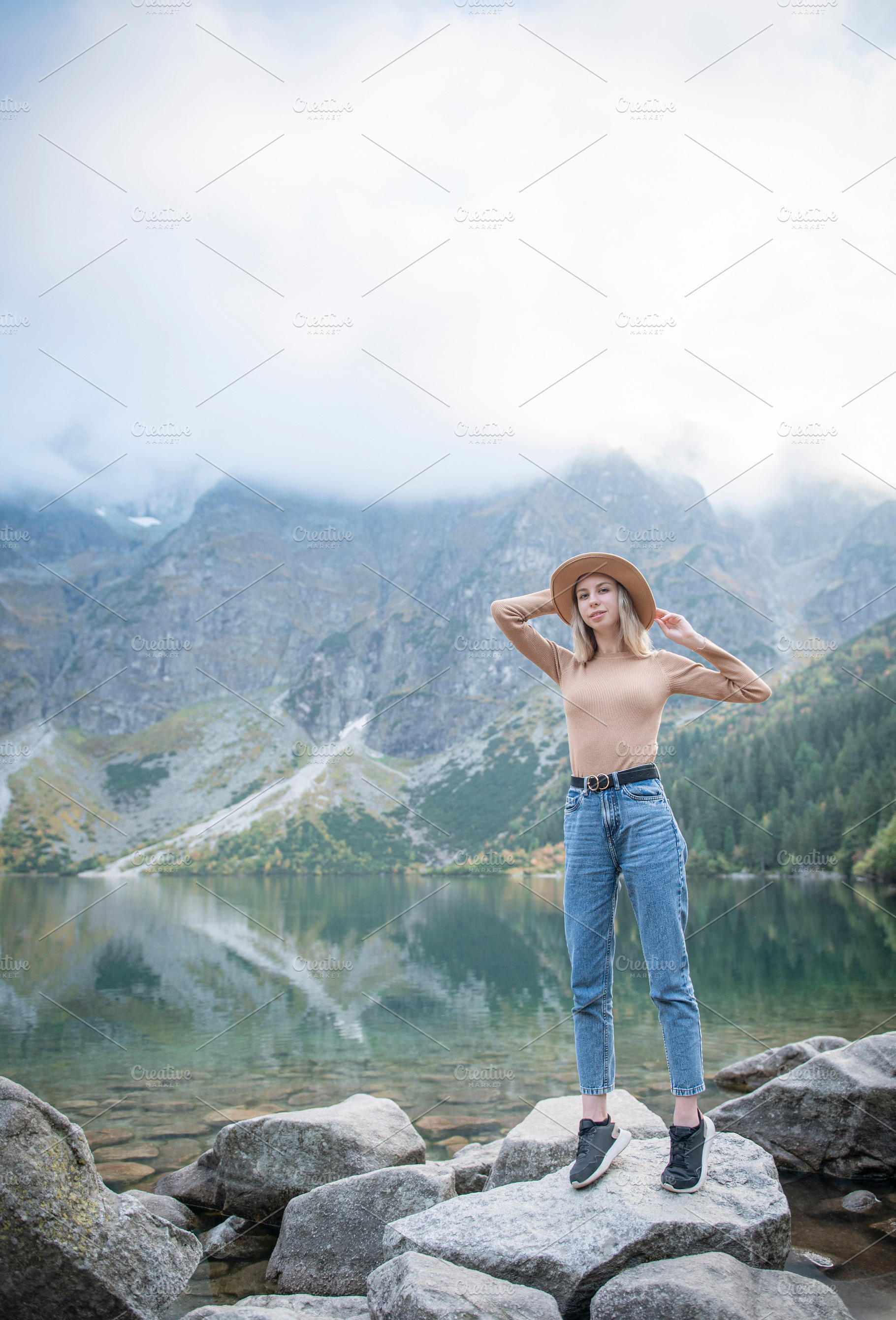 Young tourist woman in a hat with hands up on the top of the mou, a Sports & Recreation Photo by Olena Rudo