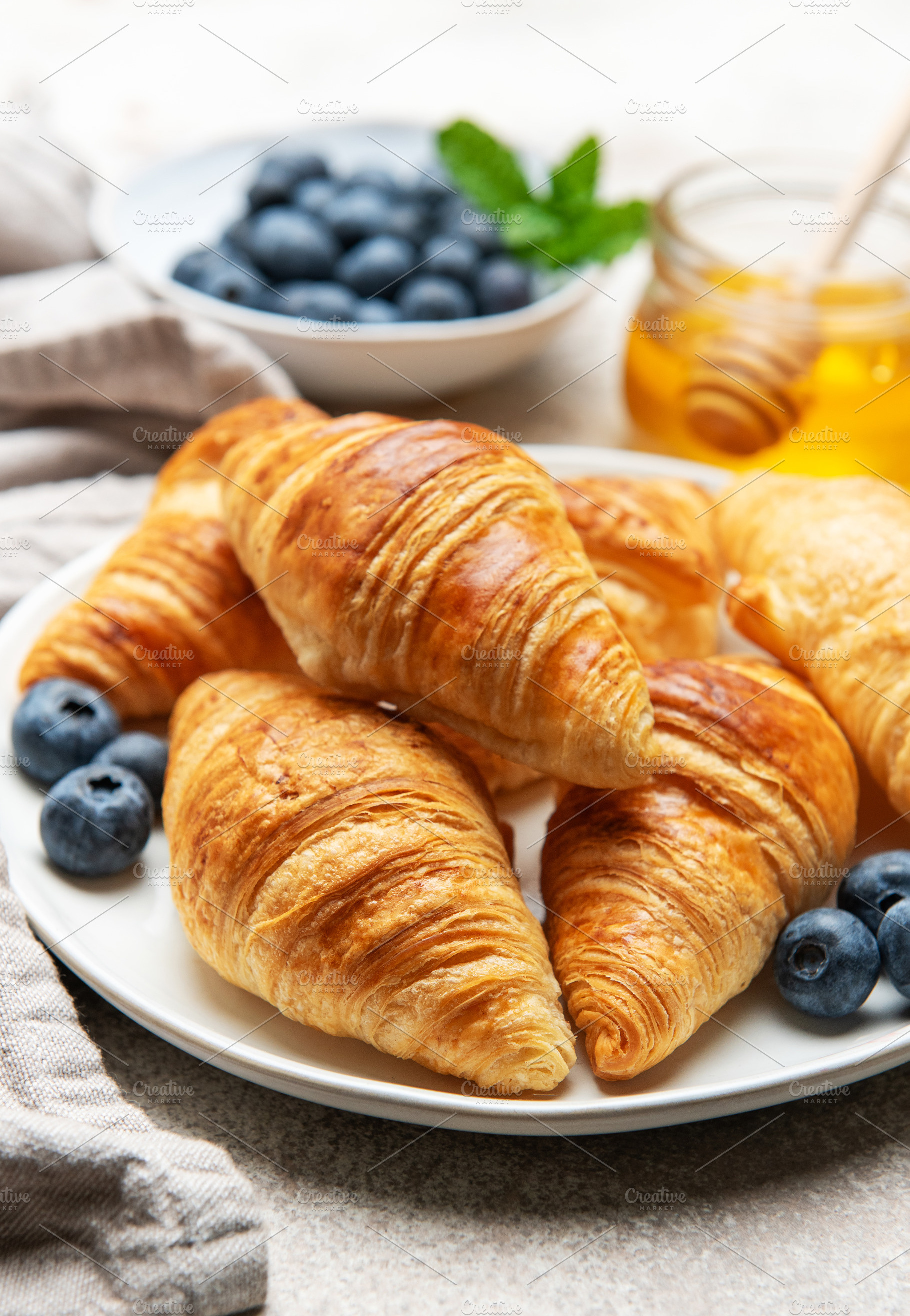 Freshly baked croissants with blueberries and honey for breakfas, a Food & Drink Photo by Olena Rudo