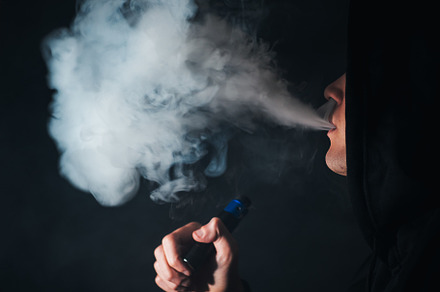A young man exhales a cloud of steam using an electronic cigarette. Alternative, a Person Photo by PavelKant