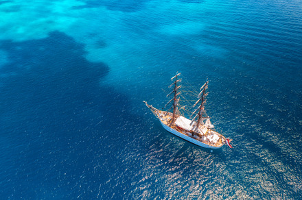 Aerial view of beautiful sailboat in blue sea at sunset in summer, a Nature Photo by den-belitsky