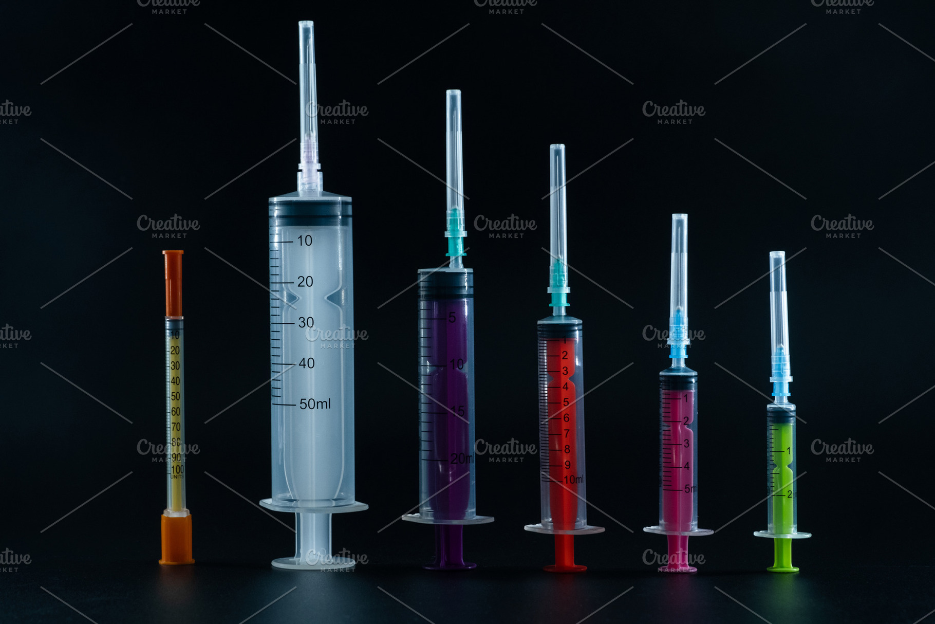 A composition of various size syringes on a dark background, highlighting theme, a Health & Medical Photo by Rohan Photography
