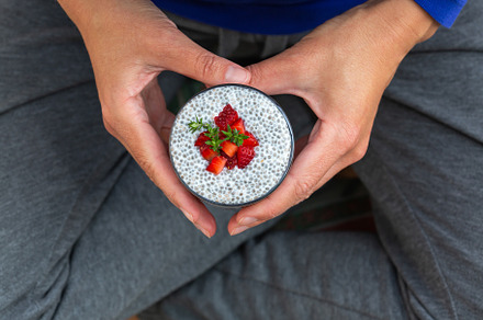 Female hands holding chia pudding with fresh strawberries for breakfast, a Food & Drink Photo by Antonina Vlasova