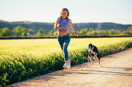 Beautiful young blonde woman running in the field with her greyhound dog., a Person Photo by karrastock