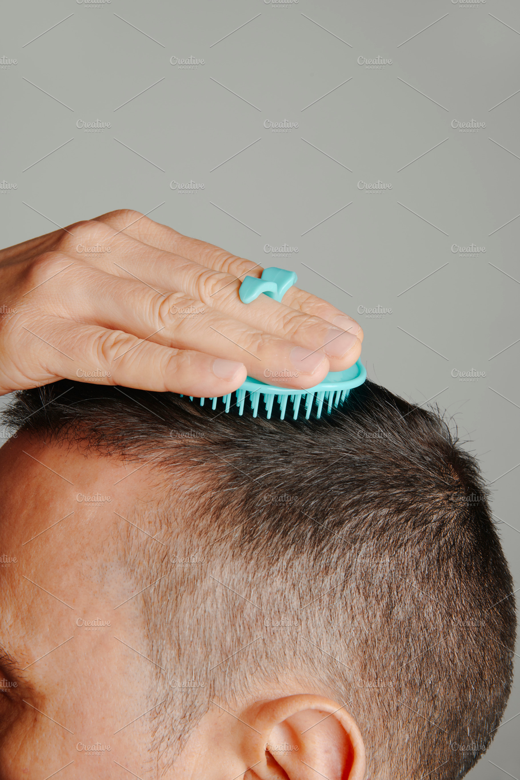 man combs his hair with a round scalp brush, a Photo by Nito