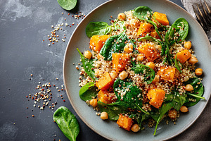 Healthy quinoa salad with spinach and roasted squash served in a bowl, a Photo by AlyaAnd