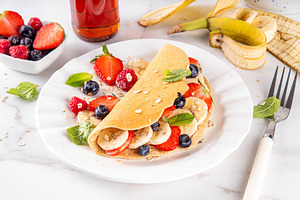 Tasty stuffed oatmeal banana pancake with fresh fruits and berri, a Food & Drink Photo by Rimma