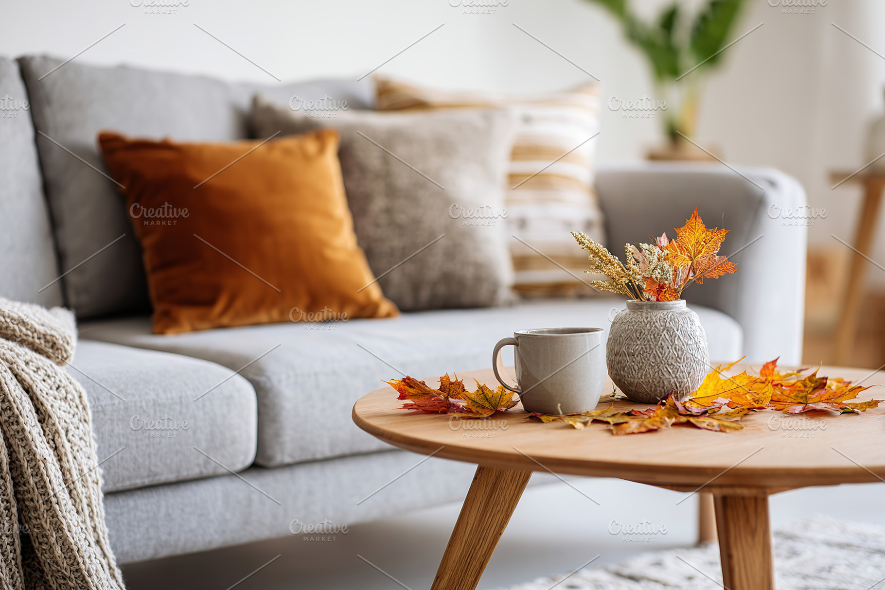 Light grey sofa in a cozy living room corner adorned with autumn decor and warm, a Photo by AlyaAnd