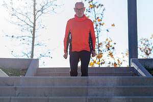 Senior man walking down stairs in a sunny outdoor park, a Sports & Recreation Photo by RF Images