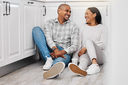 Love, happy and couple relax on a floor, talking and bonding in their home kitchen with coffee. Marriage, tea and man sitting with woman, laughing and enjoying conversation and relationship indoors, a Photo by Peopleimages.com