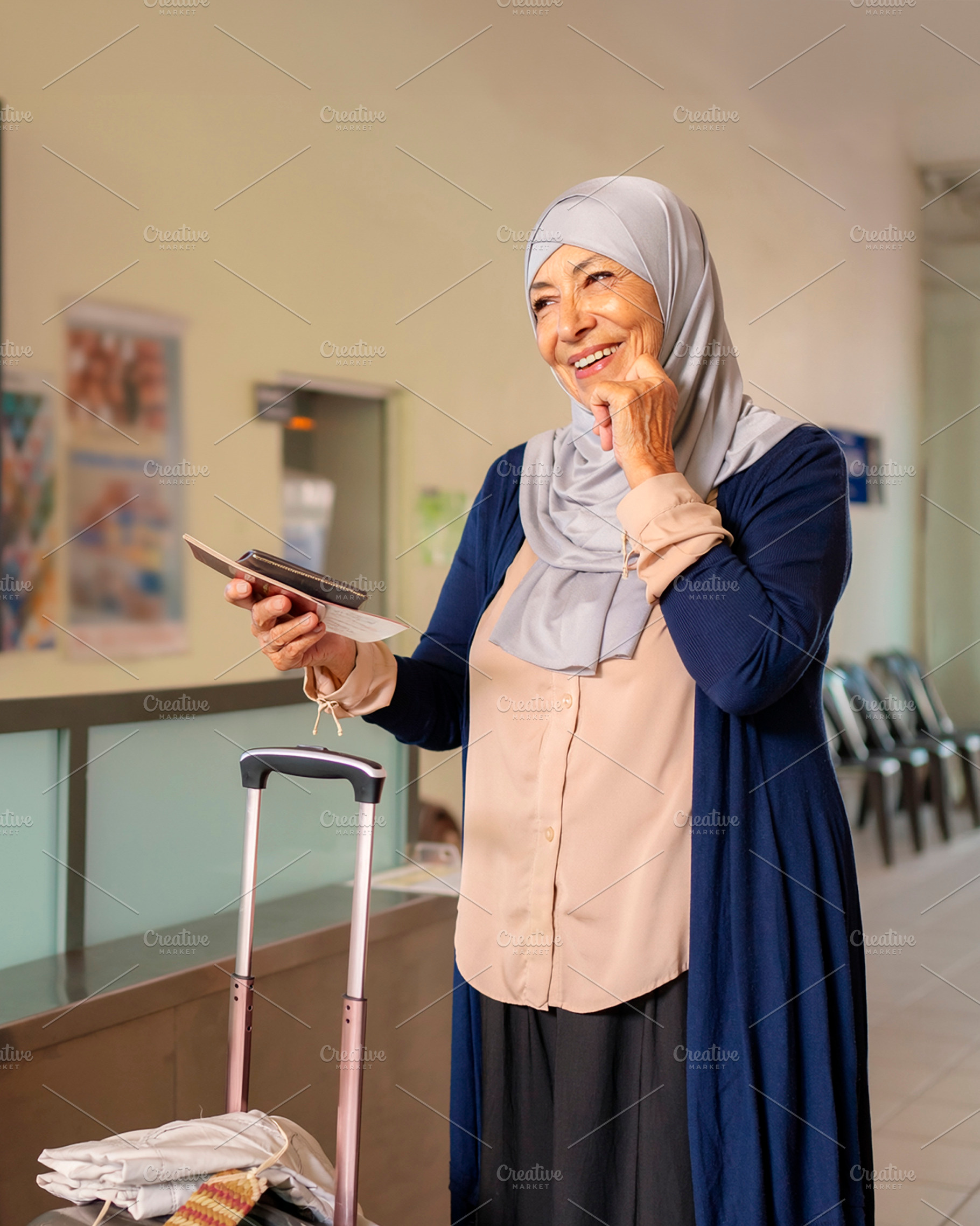 Senior traveler wearing a headscarf standing beside rolling lugg, a Person Photo by DanFLCreativo