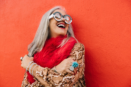 Cheerful senior woman laughing happily against a red wall, a Person Photo by Jacob Lund