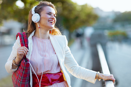 happy elegant woman in pink dress and white jacket in city, a Person Photo by Alliance Images