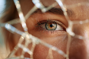 Intense close-up of a woman's eye seen through shattered glass during daylight, a Background Photo by AlyaAnd