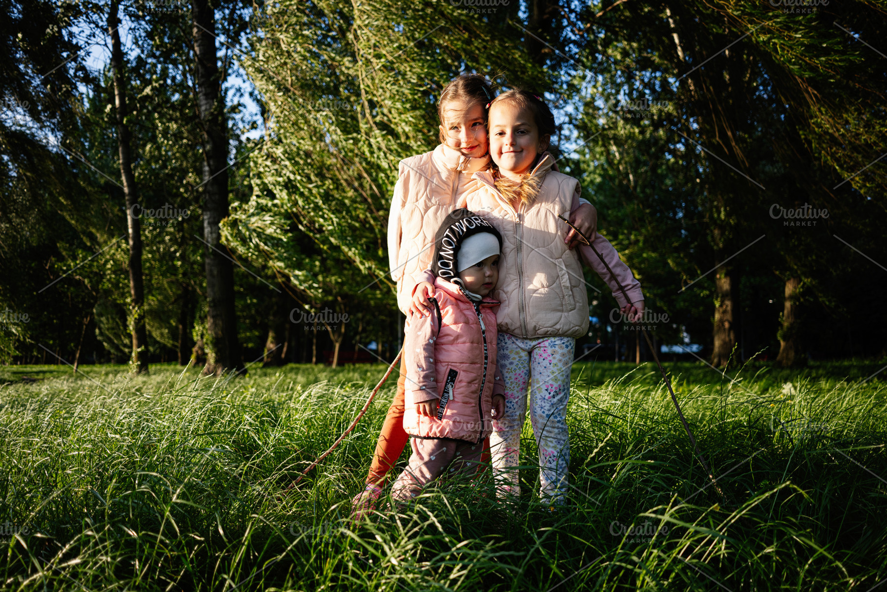 Three children playing outside on a sunny day in a green grassy field, a Photo by AS photostudio