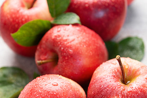 Fresh red apples with water drops and green leaves on gray backg, a Food & Drink Photo by Olena Rudo