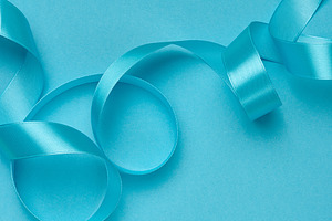A satin blue ribbon folded in graceful waves and curls on a soli, a Holiday Photo by ndanko