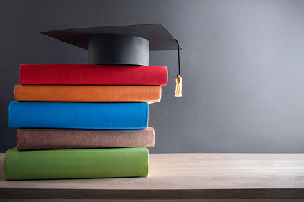 Graduation concept with mortarboard on stack of books on table