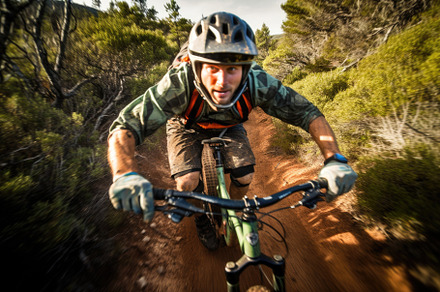An action shot of a mountain biker speeding downhill on a rugged, a Sports & Recreation Photo by designvectx