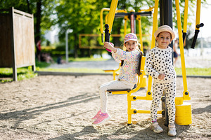 Two children playing on outdoor gym equipment in a sunny park setting, a Person Photo by AS photostudio