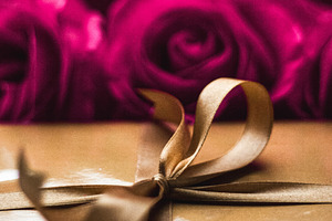 Golden gift box with a bow and red roses in the background, symb, a Photo by Studio ANNA