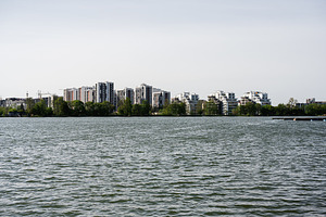 Modern residential buildings along a serene lake under a clear sky, a Photo by AS photostudio