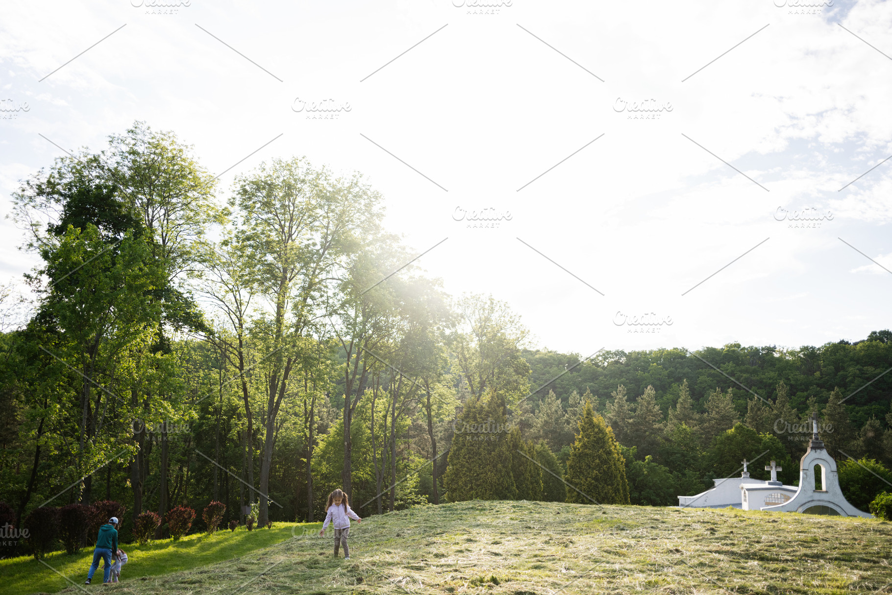 Sunny meadow with trees, a family strolling, and a scenic white building, a Person Photo by AS photostudio