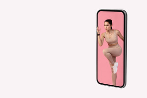 Sporty Lady Exercising Jumping From Smartphone Screen Over Gray Background, a Photo by Prostock-Studio