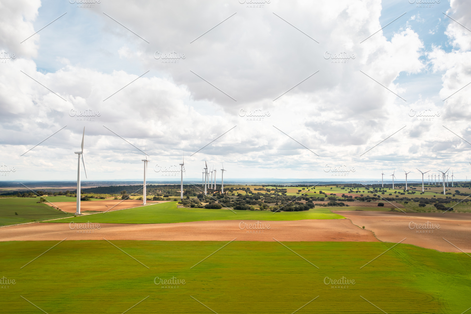 Vast solar and wind energy farm under bright cloudy sky, a Photo by andreonegin market