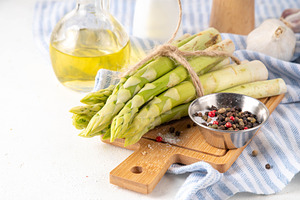Raw fresh organic asparagus stems on kitchen table background, a Food & Drink Photo by Rimma