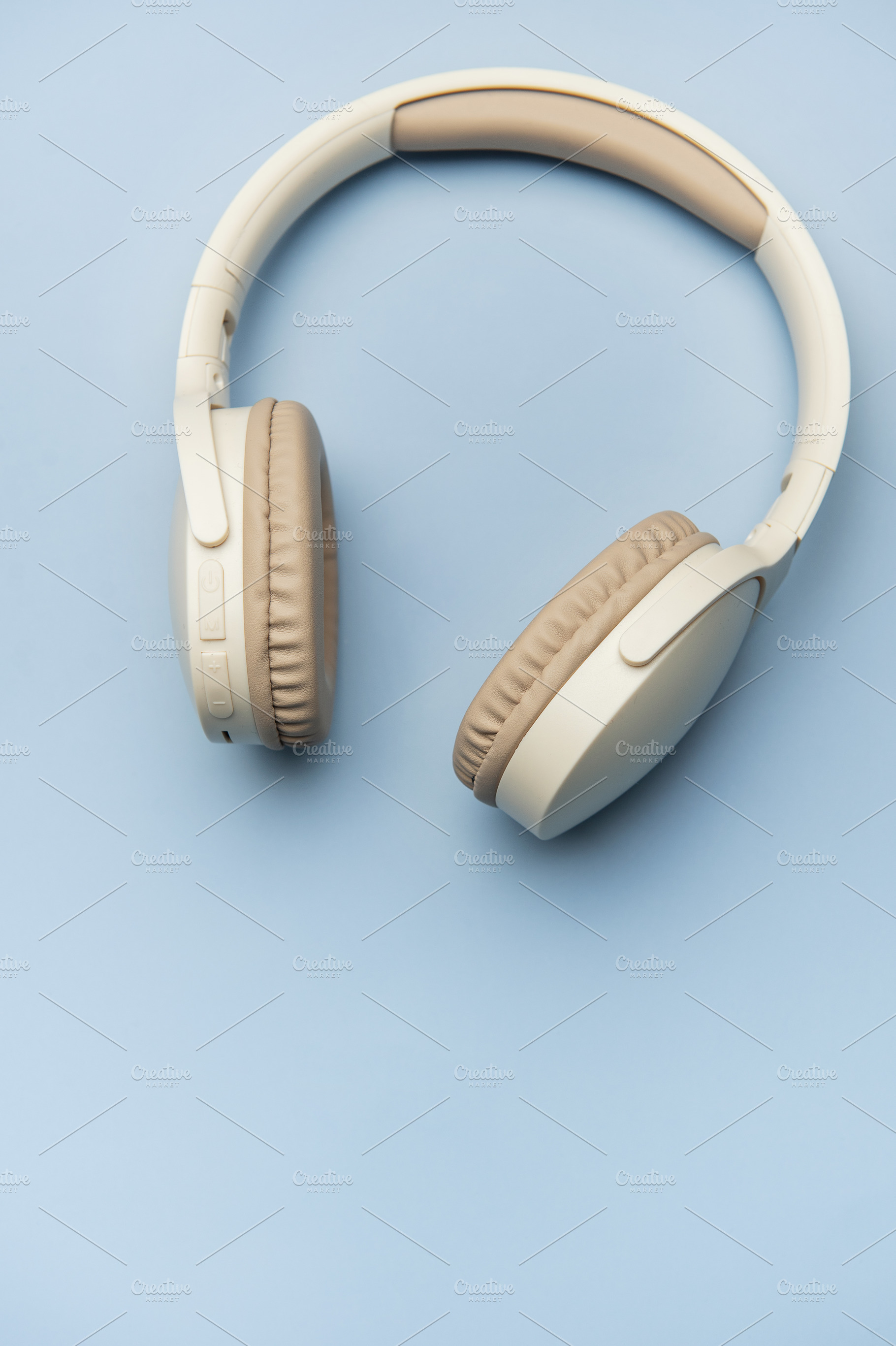 Modern wireless headphones lying on minimalist blue background, a Technology Photo by Olena Rudo