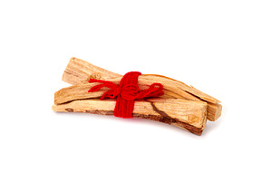 a bundle of sandalwood sticks tied with red yarn, a Photo by Nito