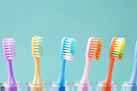 New toothbrushes in glasses on blue background, a Health & Medical Photo by AlyaAnd